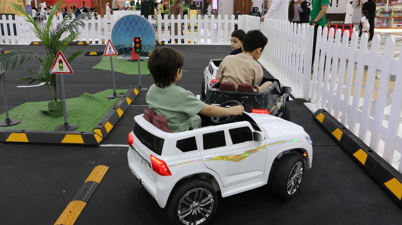 Children driving toy cars on a road-safety learning track